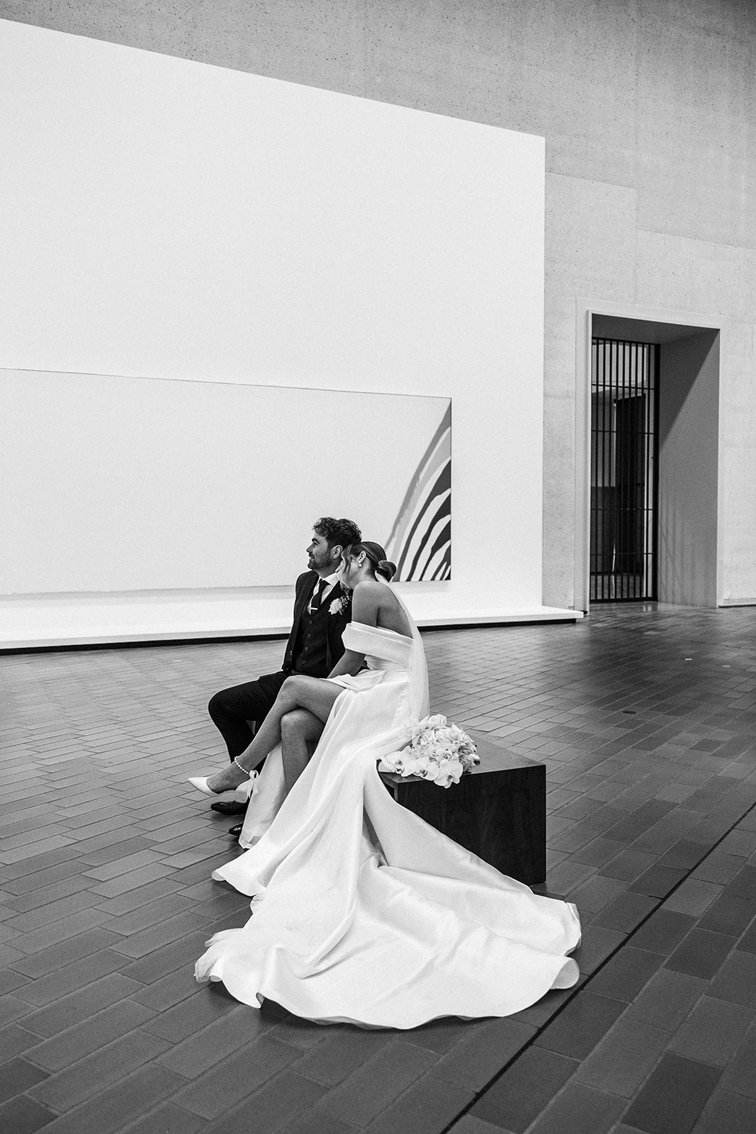Bride leaning on groom while seated and admiring the art at the National Gallery of Australia
