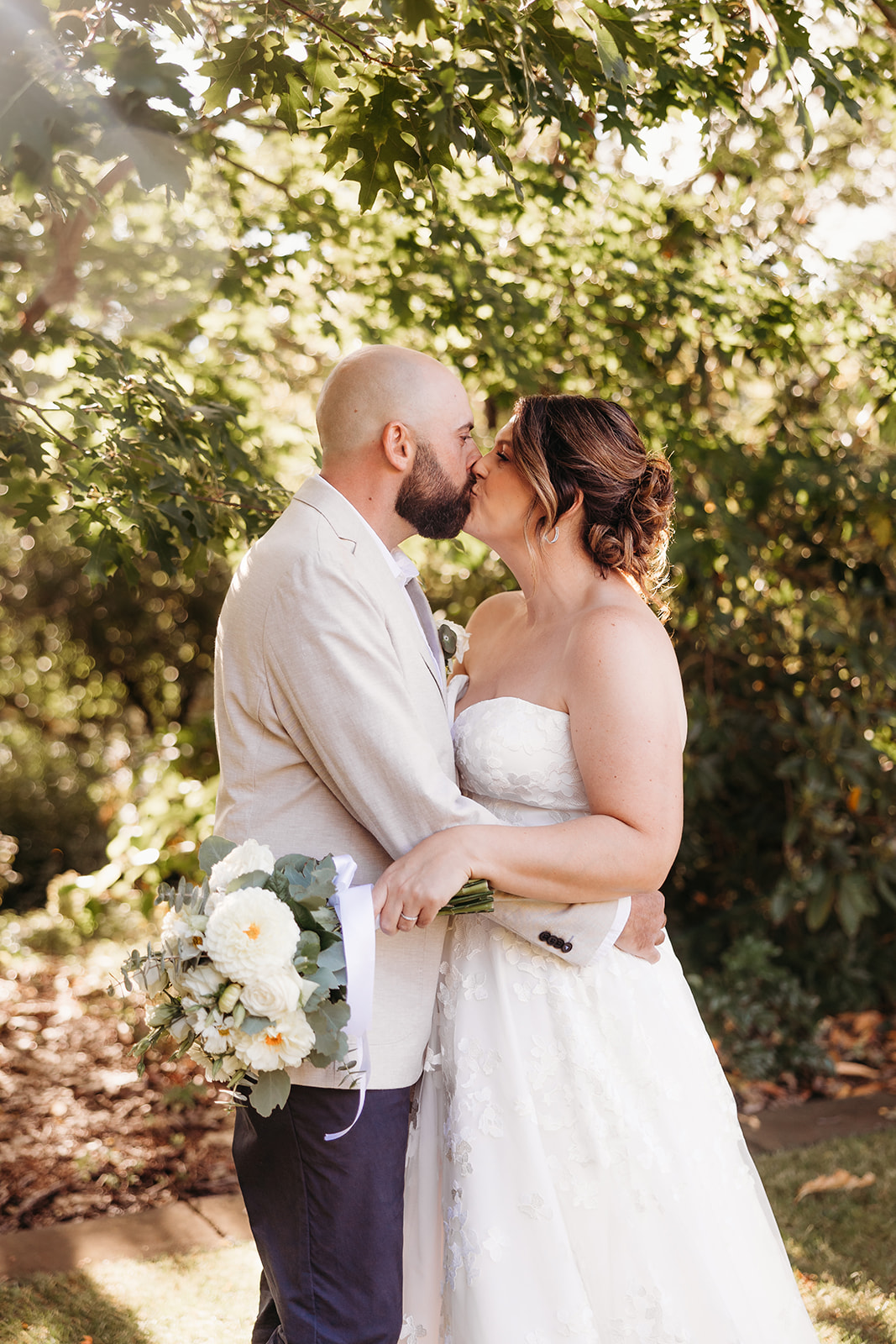 Bride and groom share a kiss in the gardens by Ginninderry Homestead, Macgregor near Canberra, ACT.