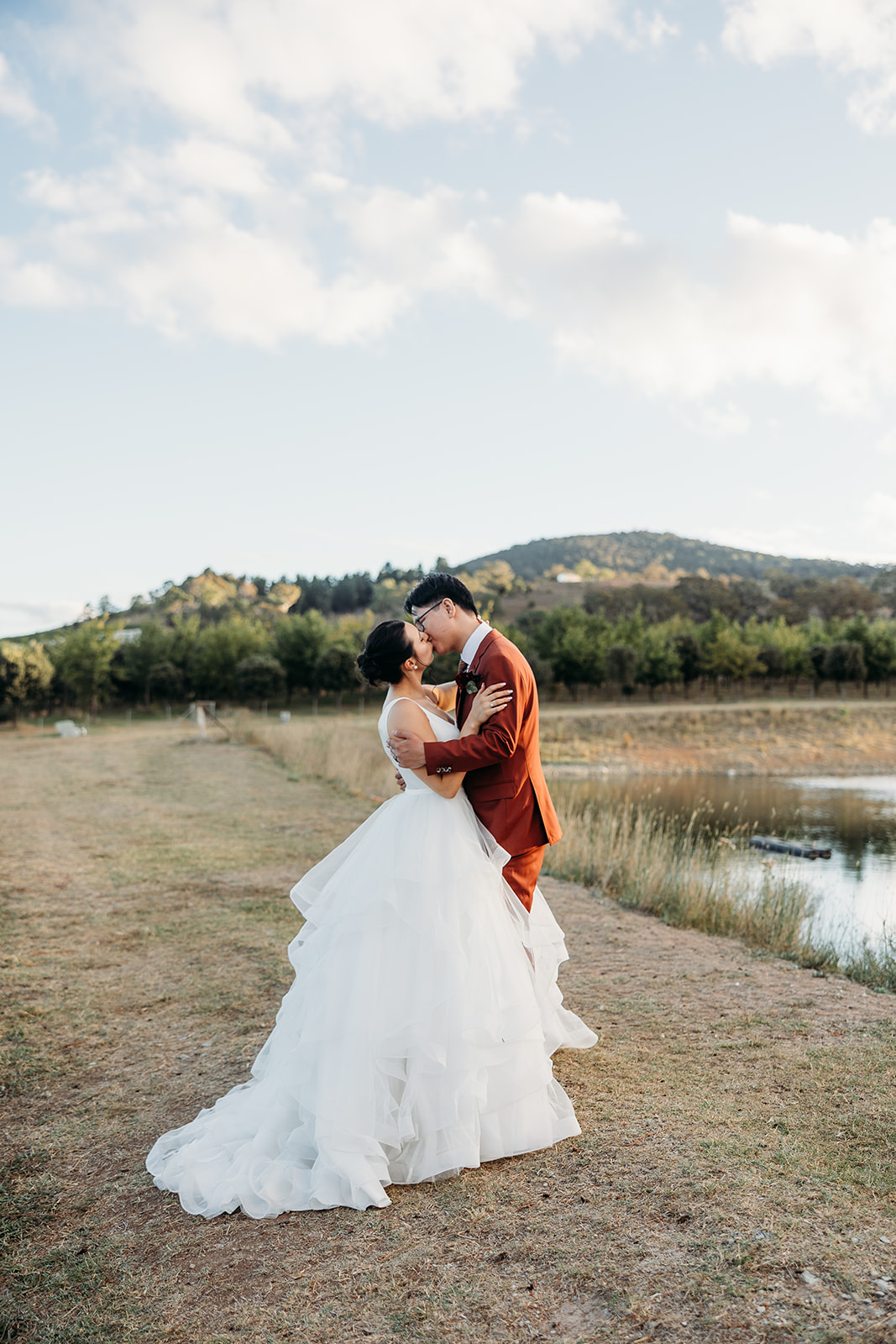 Bride and Groom share a kiss at sunset with Mount Majura, Canberra in the background. A beautiful view from The Truffle Farm.