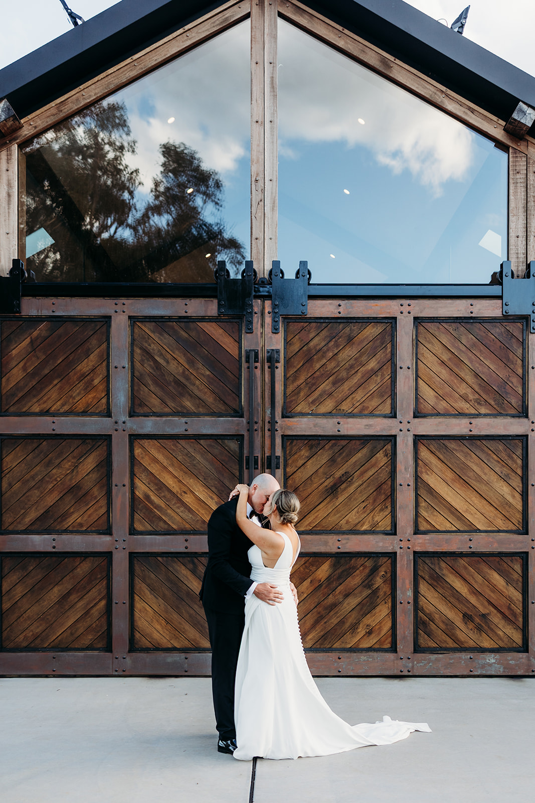 Bride and Groom share a kiss in front of the beautiful barn doors at The Truffle Farm, Canberra ACT.