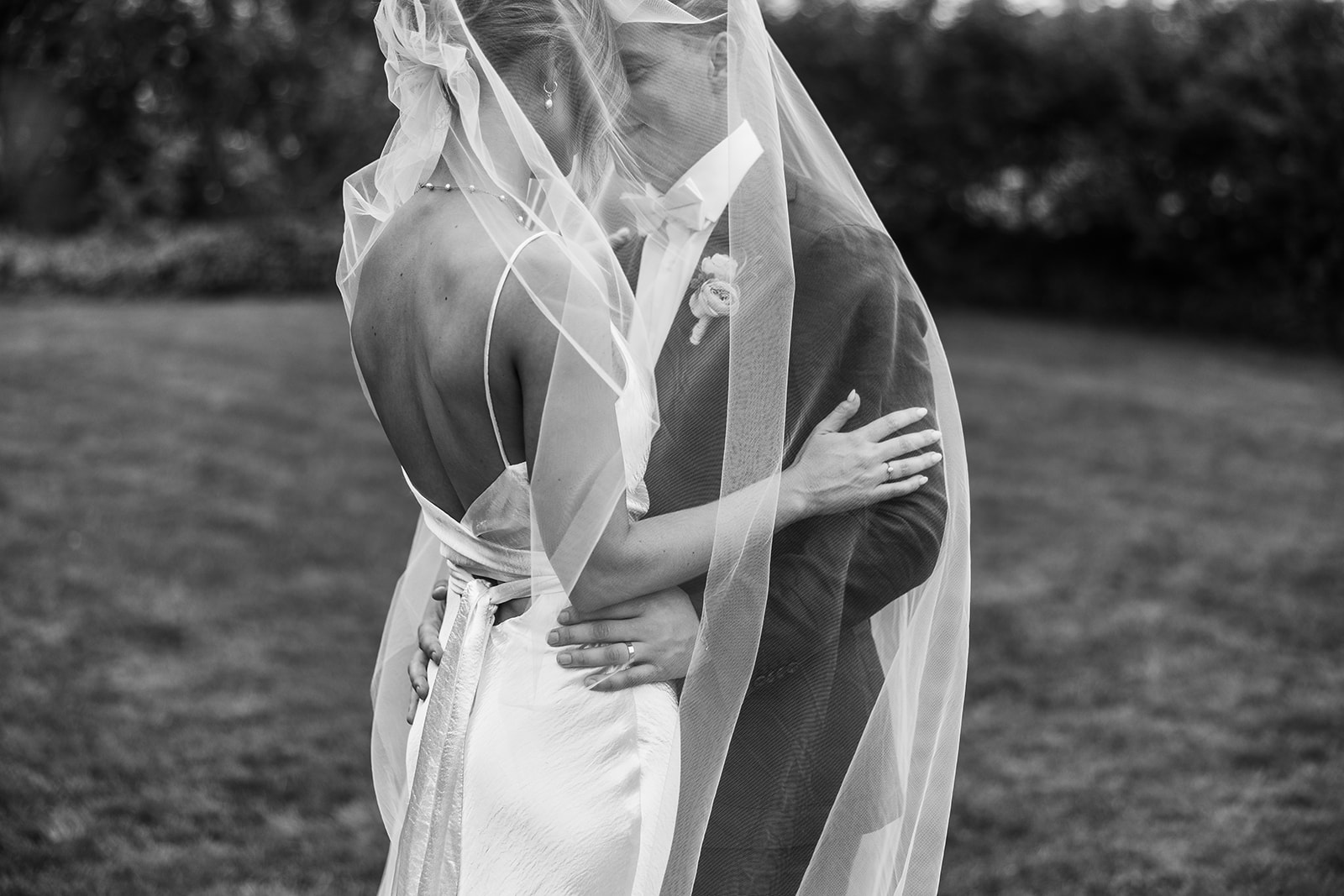 Close up of bride and groom face to face, under the bride's veil holding each others arms. Shown in black and white. Photo by Acacia & Grace Photography