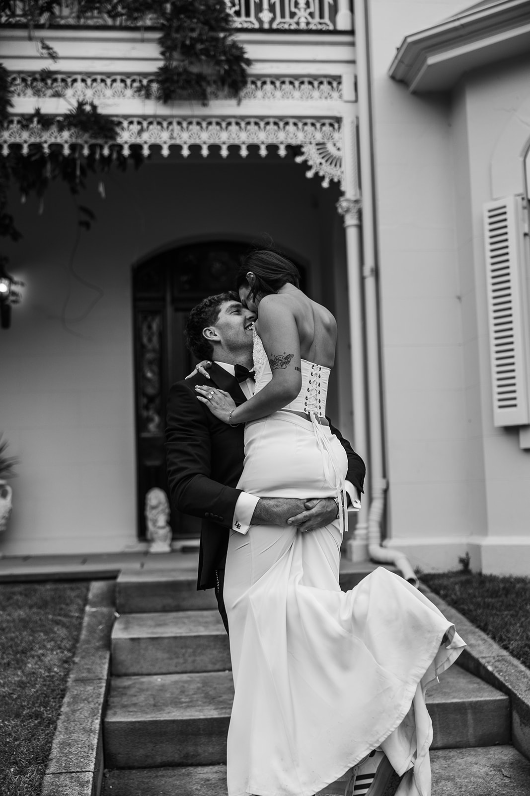 Blurred black and white image of groom lifting bride. Taken on the porch of Somerley House in the NSW Southern Highlands by wedding photographer, Acacia & Grace Photography.
