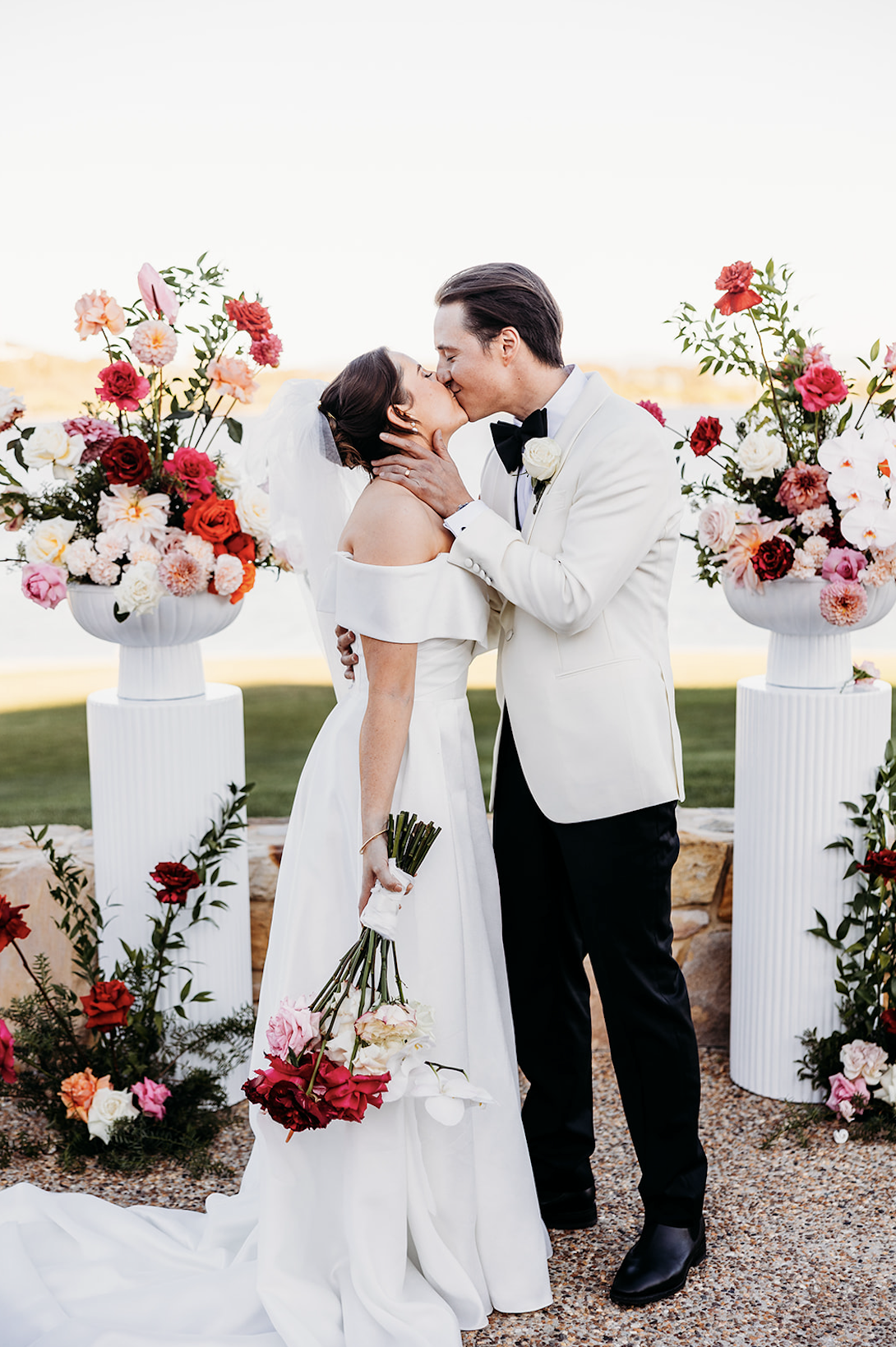 Bride and groom first kiss in front of their epic floral arrangements at The Marion, Canberra ACT